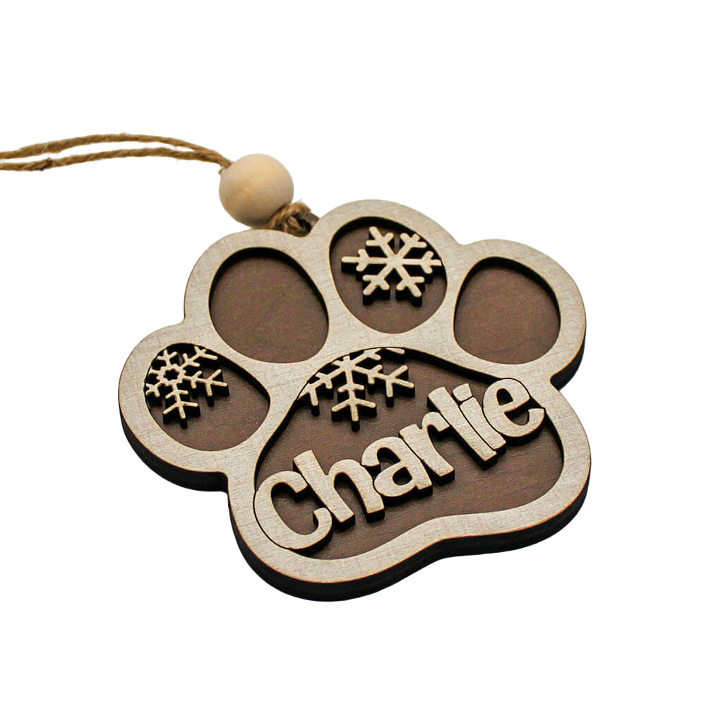 Wooden ornament shaped like a paw print with 'Charlie' and snowflake designs on a white background