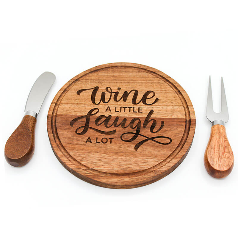 Wooden cutting board with 'Wine a little, Laugh a lot' text, knife, and fork on a white background