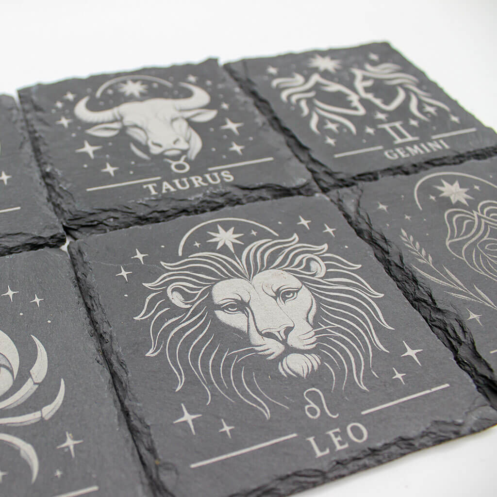 Set of slate coasters with zodiac designs on a white background