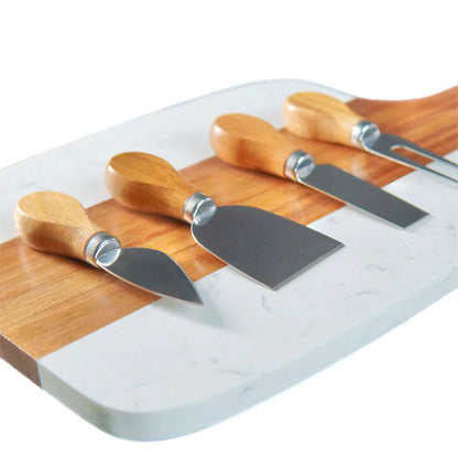 Set of four cheese knives with wooden handles on a marble cutting board.